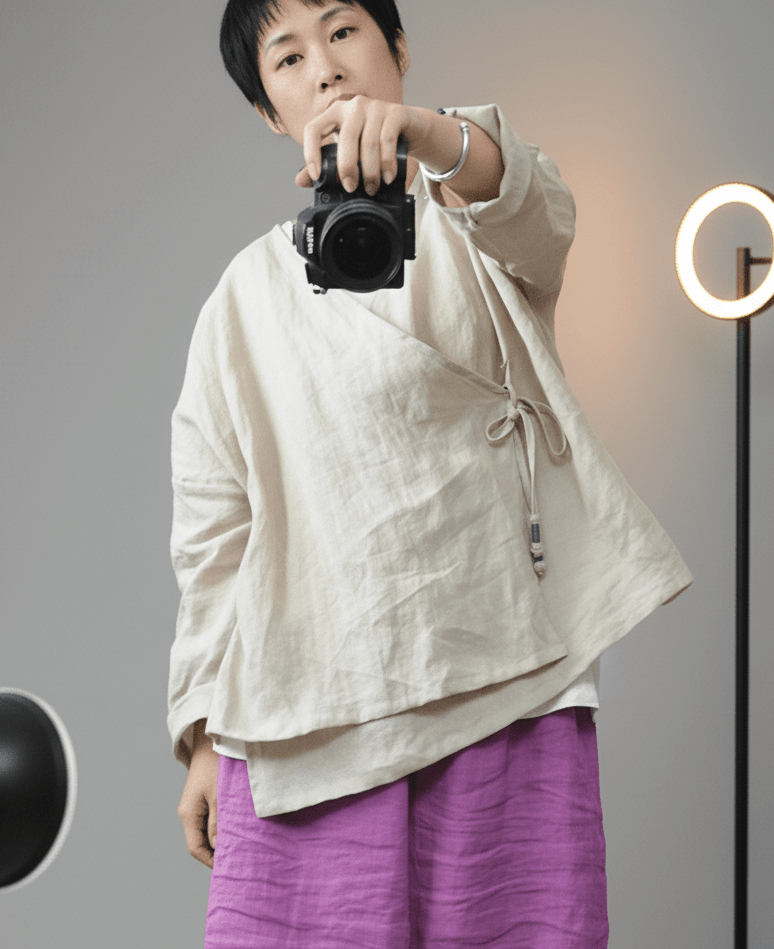 Person holding a camera against a gray background