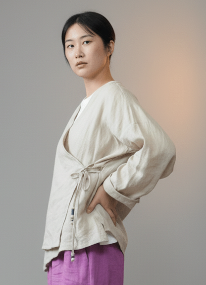 Woman wearing beige ramie v-neck boho blouse purple pants against a gray background