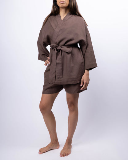 Person wearing a brown robe and shorts on a white background