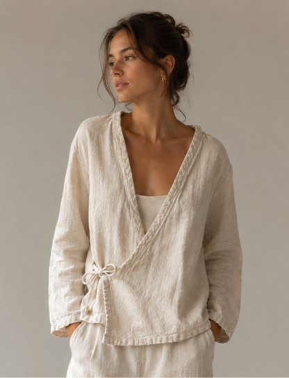 Woman wearing a beige wrap-style top and pants against a neutral background
