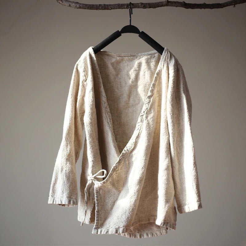 Beige linen shirt on a hanger against a plain background