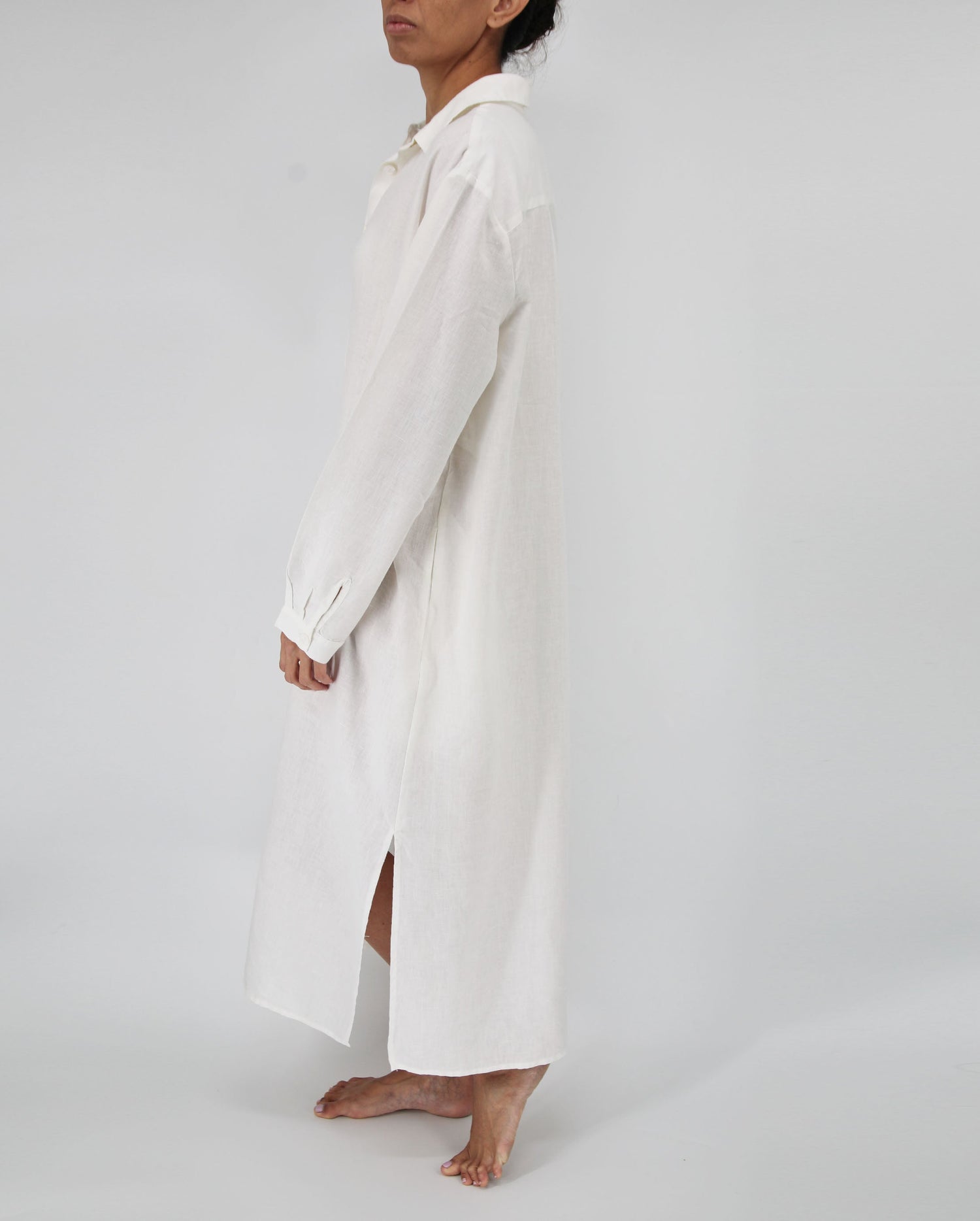 Person wearing a long white coat on a plain background