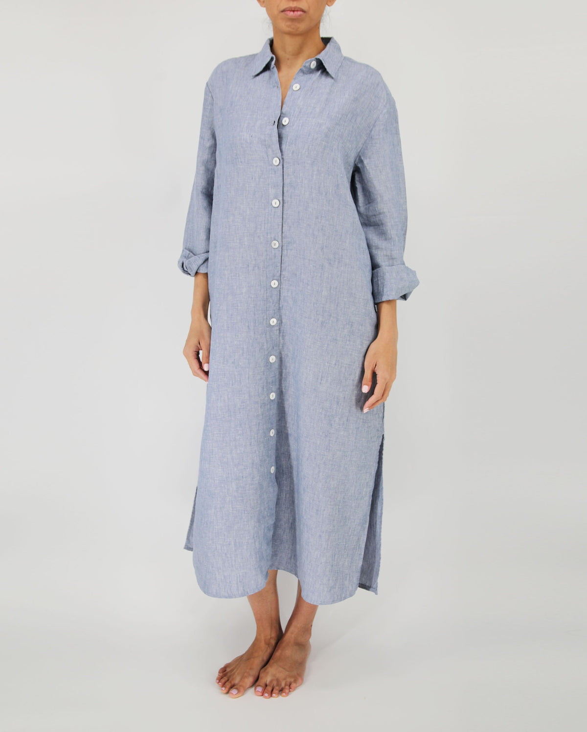 Person wearing a long blue striped shirt dress on a plain background