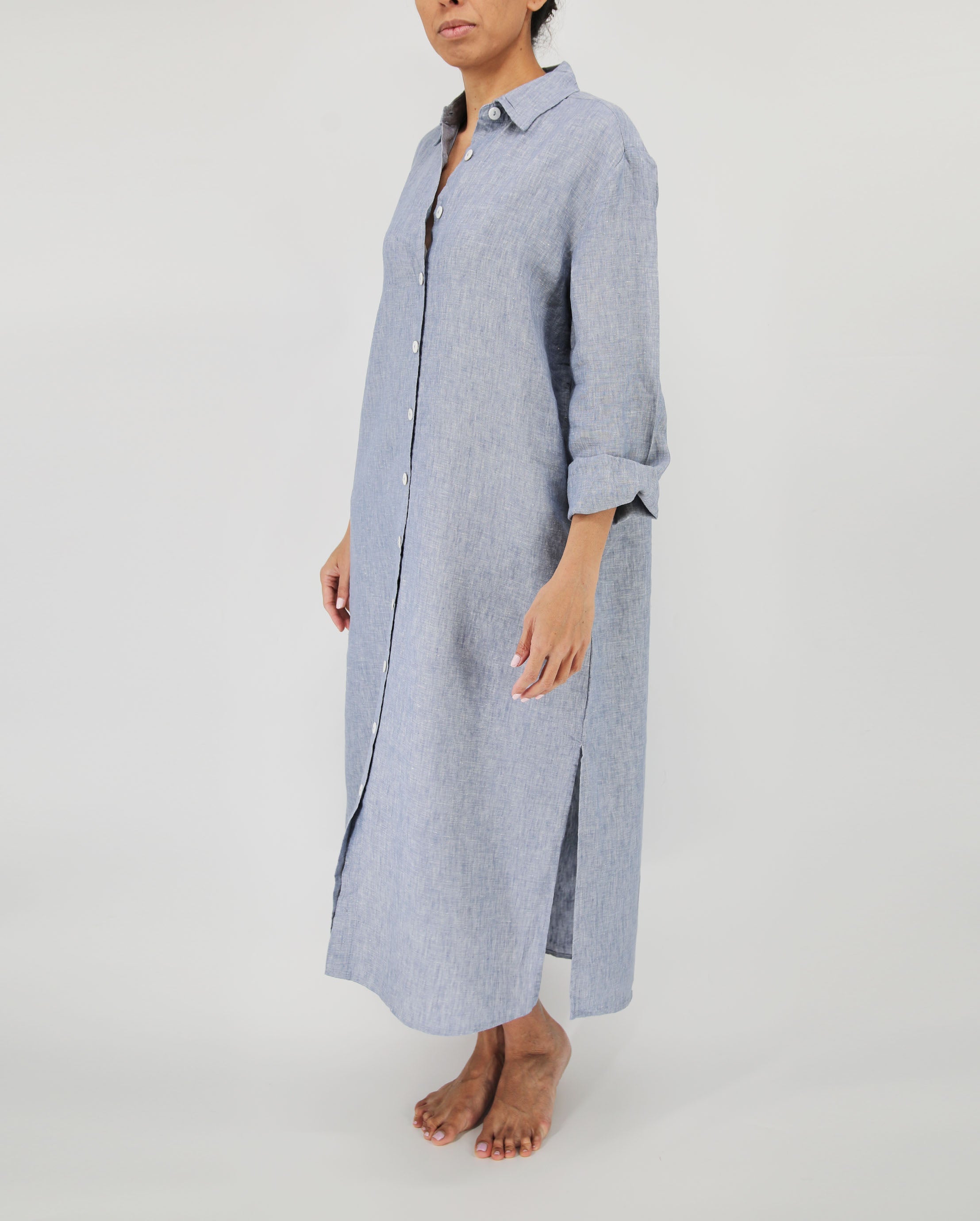 Person wearing a long blue striped shirt dress on a white background