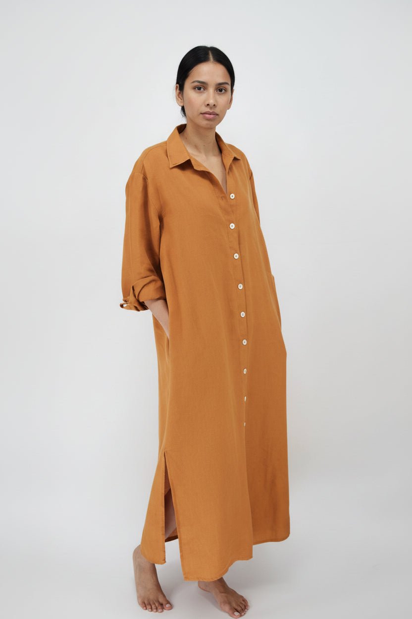 Woman wearing a long mustard yellow dress on a white background