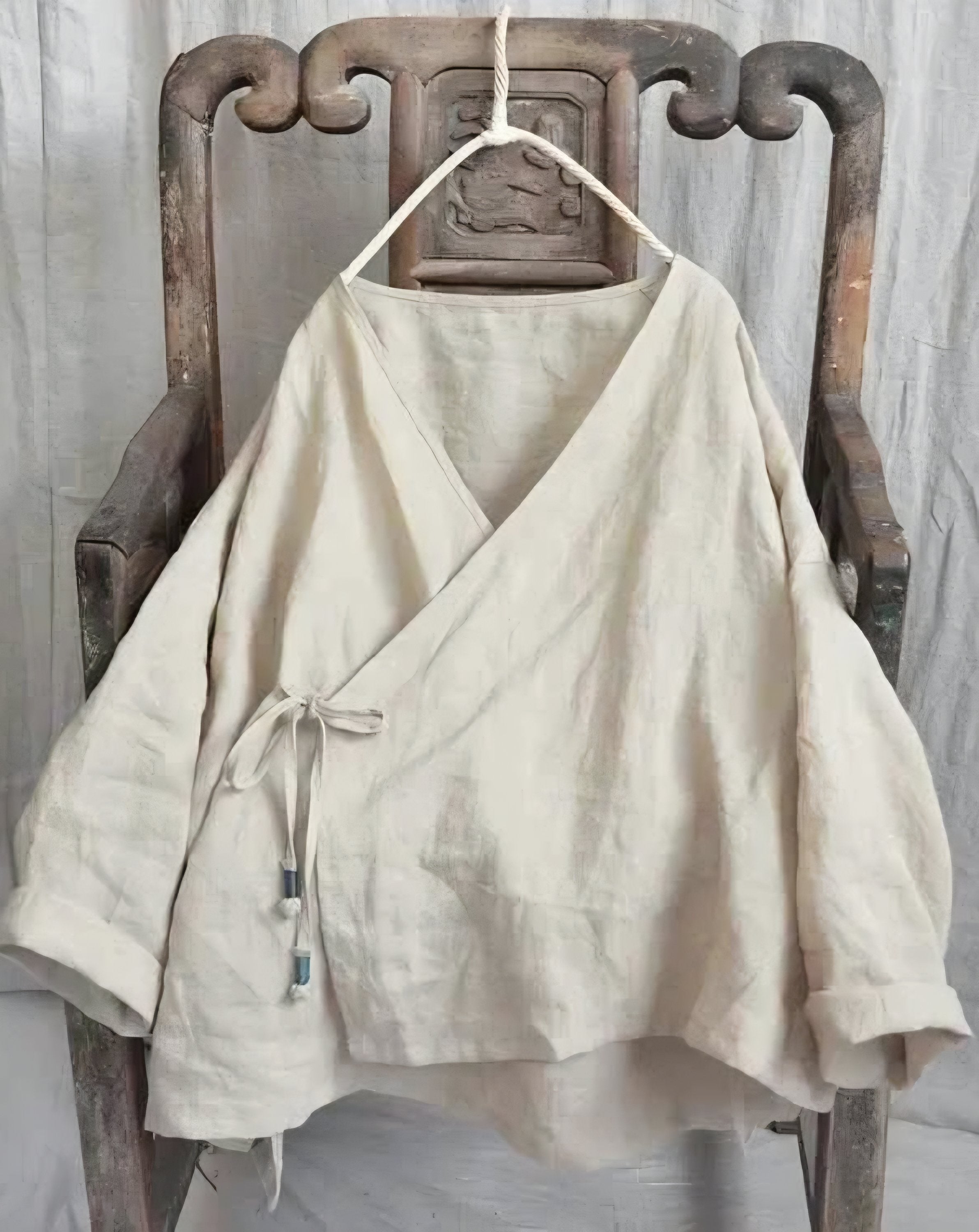 Beige top on a wooden chair with a neutral background