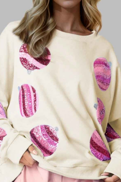 Woman wearing a cream sweater with pink heart patterns and pink shorts on a gray background