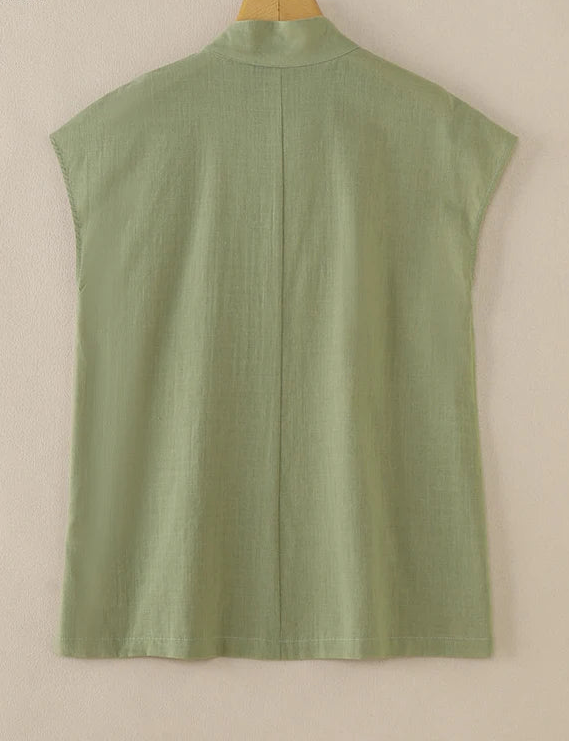 Green sleeveless shirt on a wooden hanger against a beige background, with ZANZEA branding.