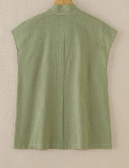 Green sleeveless shirt on a wooden hanger against a beige background, with ZANZEA branding.
