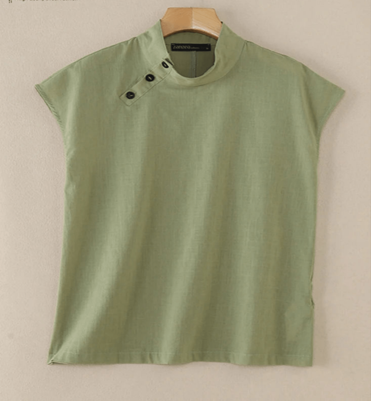 Green blouse with black buttons on a beige background