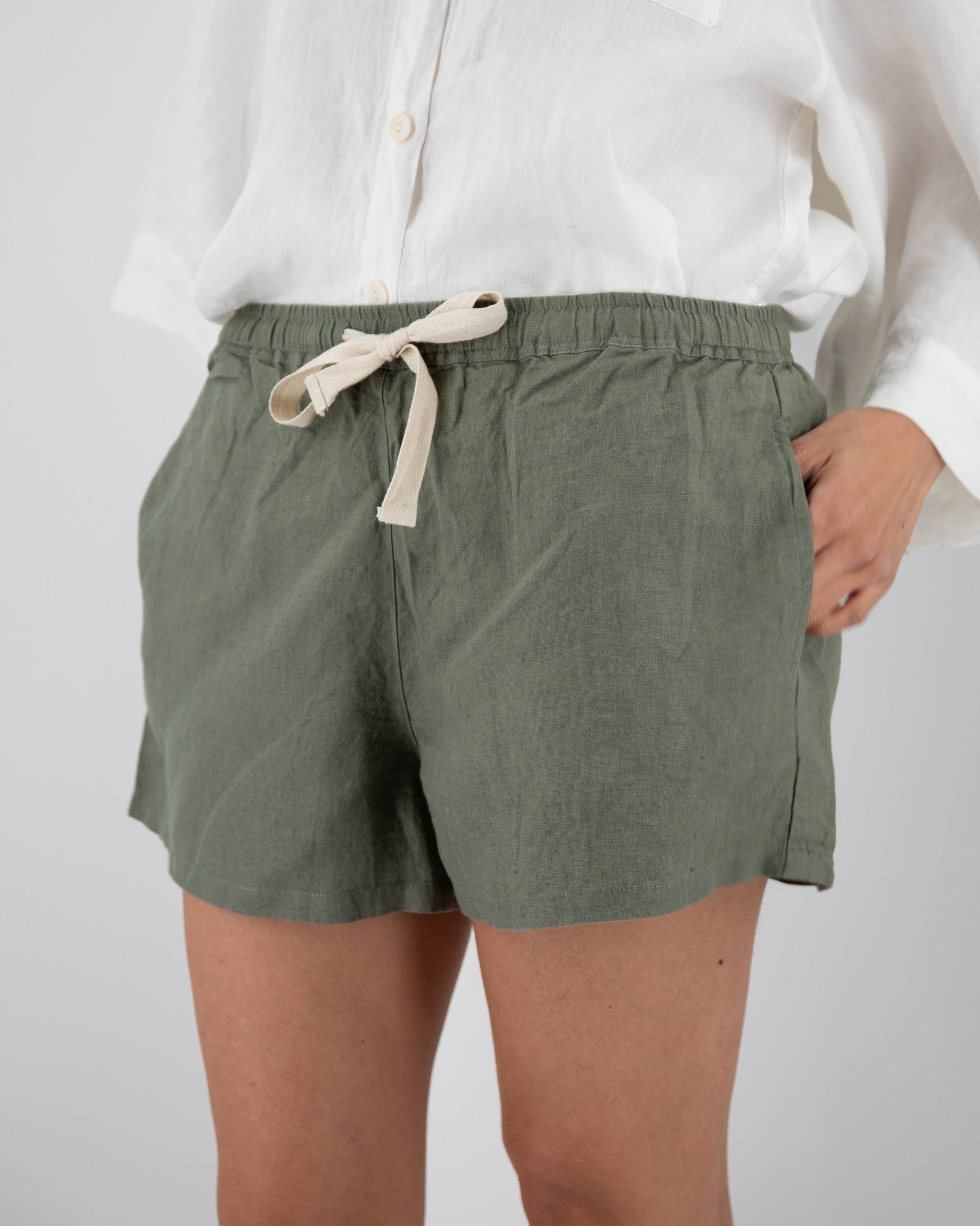 Person wearing green shorts with a white shirt on a plain background