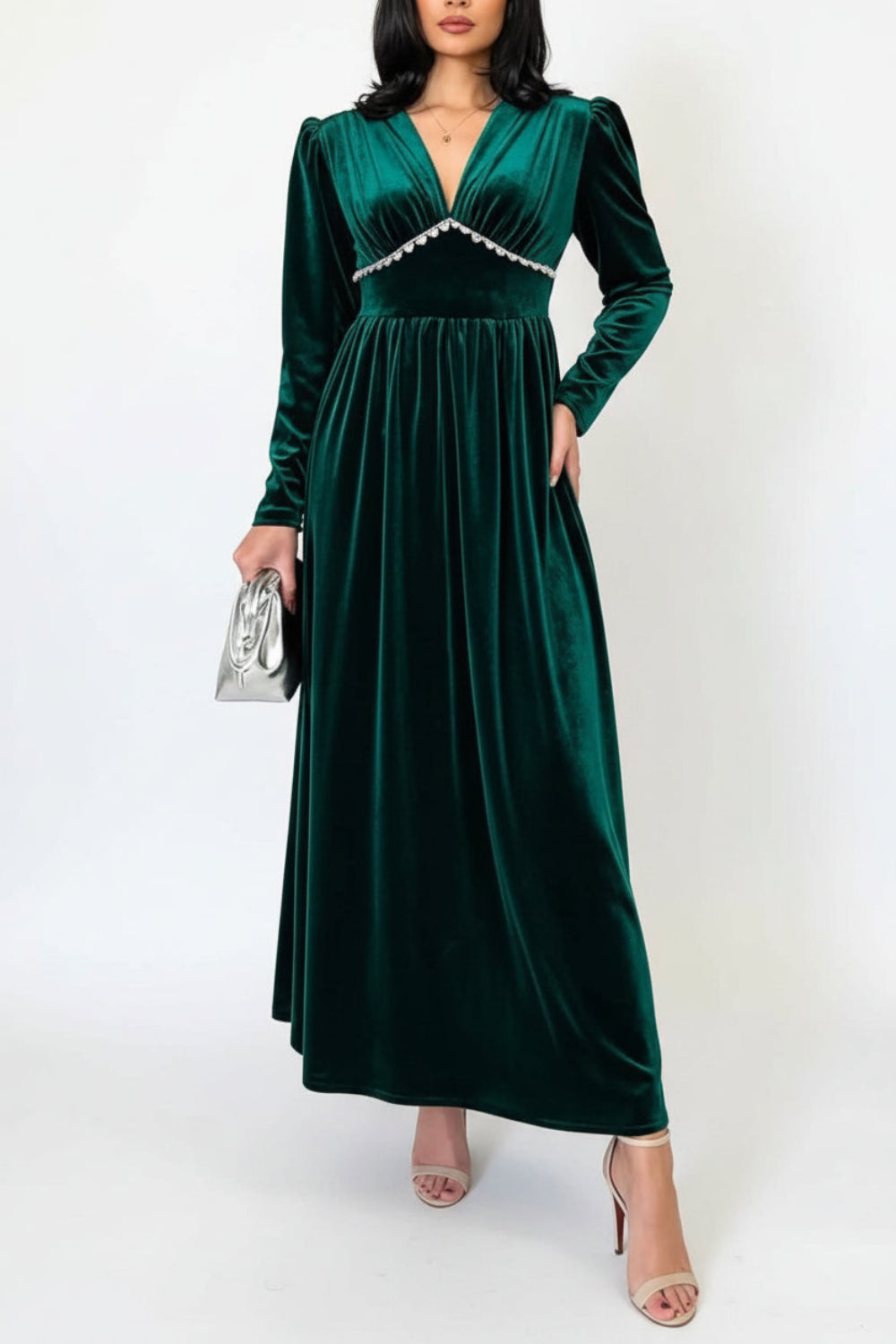 Woman wearing a green velvet dress with a textured wall and a brown curtain in the background