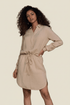 Woman wearing a beige shirt dress against a plain background