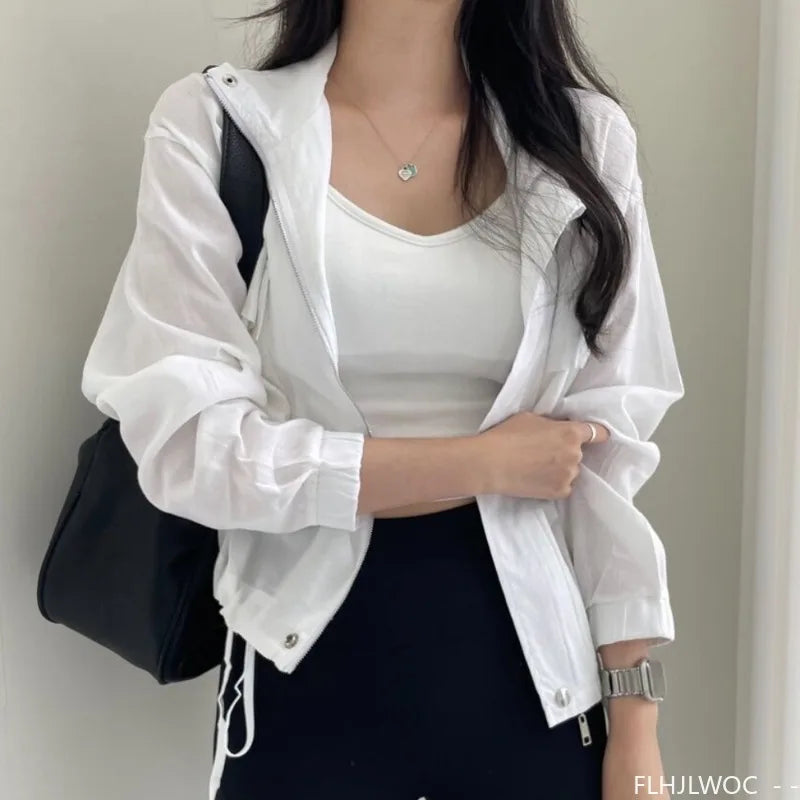 Person wearing a white jacket over a white top with a black bag on a plain background