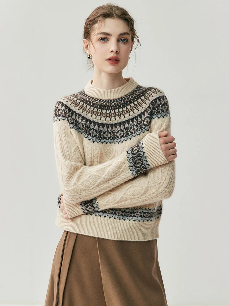 A woman modeling a cream cable-knit sweater with a dark gray and navy Fair Isle yoke pattern, paired with a brown skirt, against a light gray studio background.