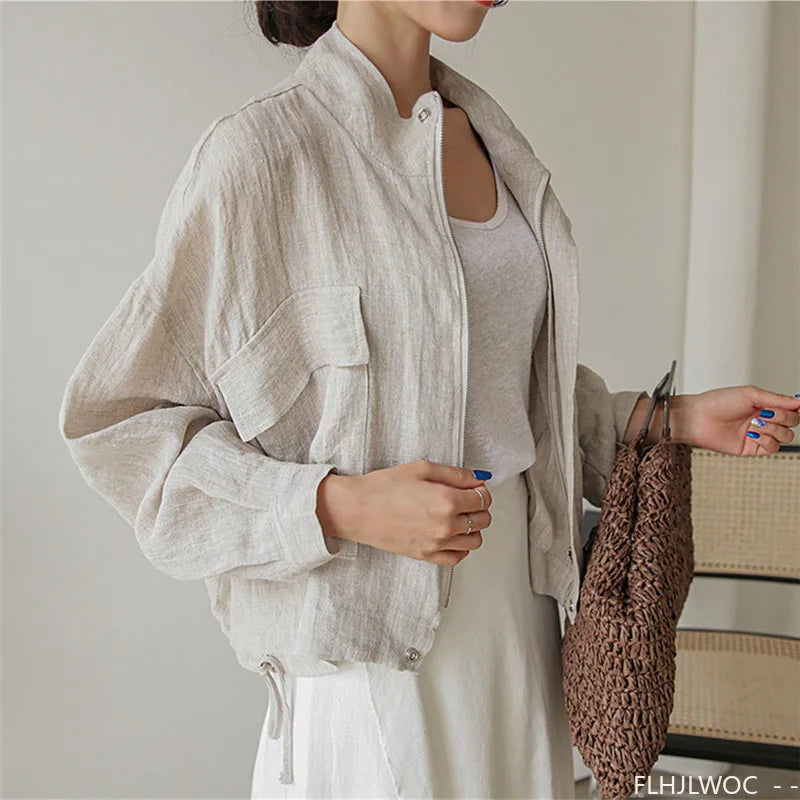Person wearing a light-colored jacket holding a woven bag indoors.