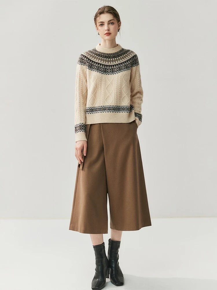 Woman wearing a cream sweater with black pattern and brown wide-leg pants on a white background