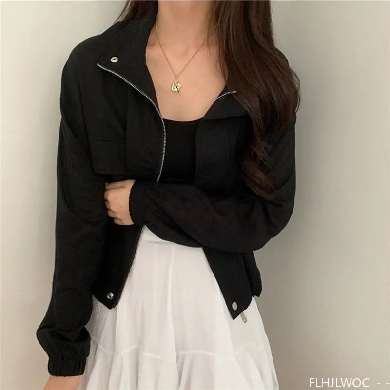 Person wearing a black jacket over a white dress against a plain background