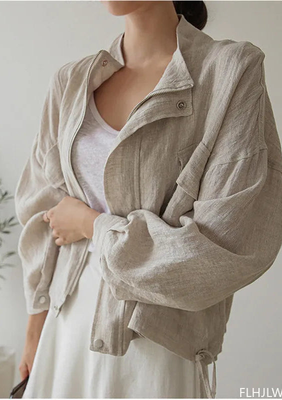 Person wearing a beige jacket indoors with a plant in the background