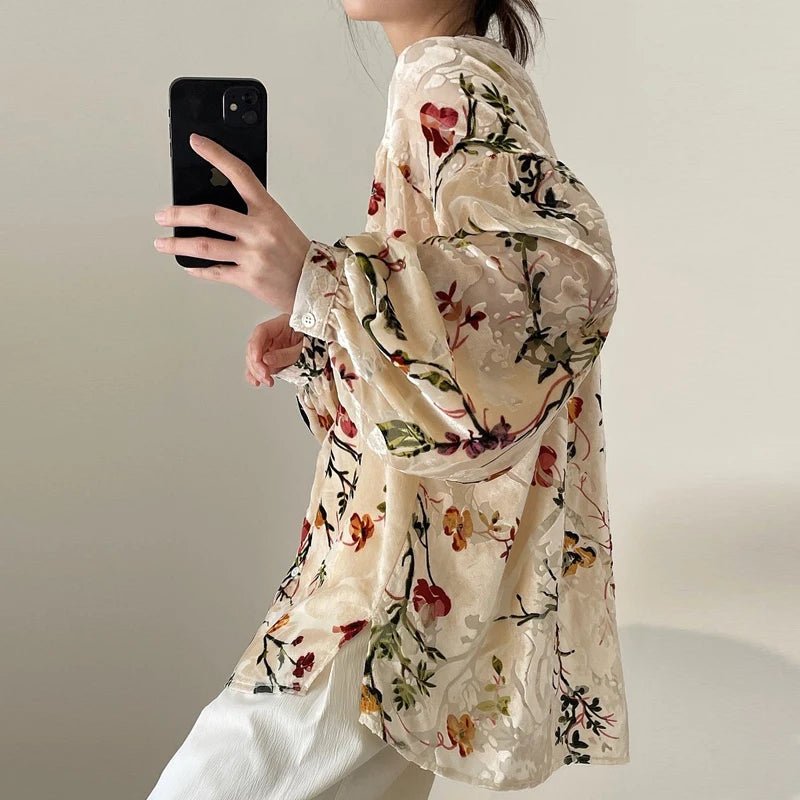 Person wearing a floral blouse taking a mirror selfie.