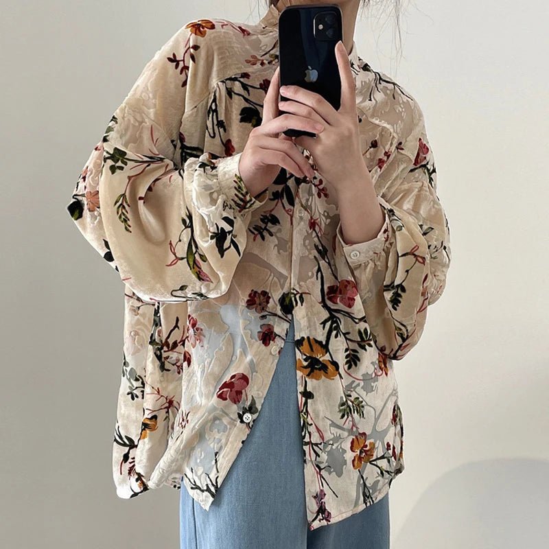 Person wearing a floral blouse taking a mirror selfie.