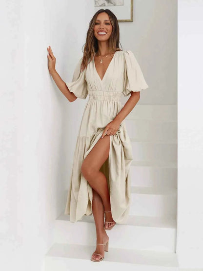 Woman in a beige tiered midi dress with short puff sleeves and a surplice V-neck.