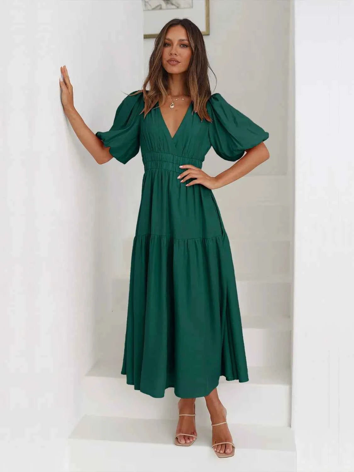 Woman in a green tiered midi dress with short puff sleeves and a surplice V-neck.