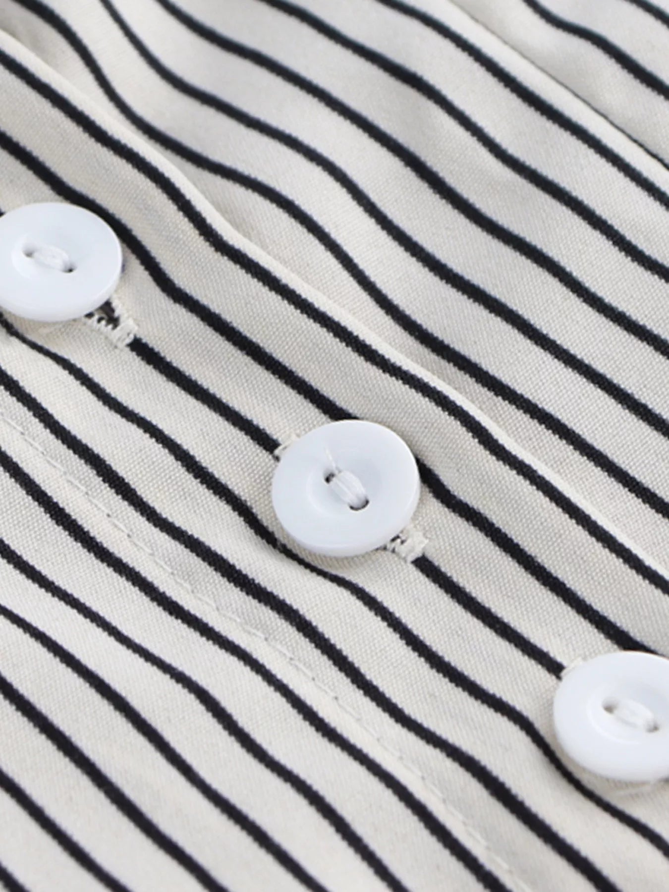 Close-up of a striped fabric with white buttons on a black and white striped background