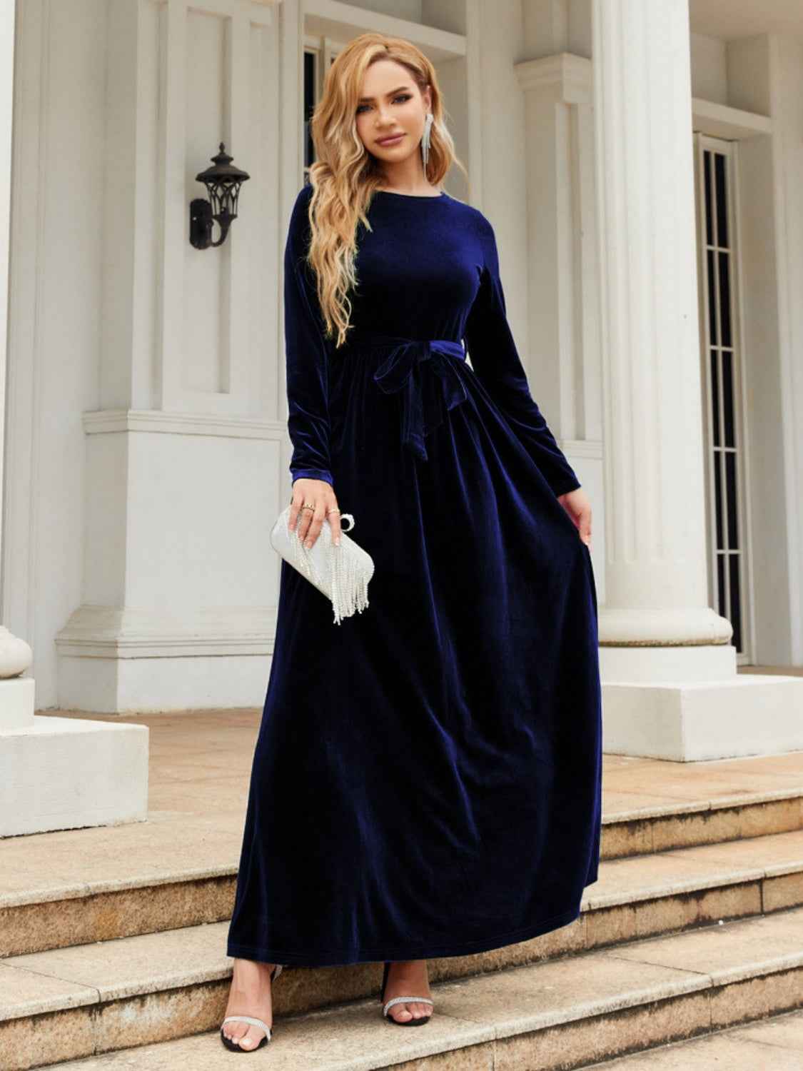 Woman in a navy velvet dress standing on steps outside a building