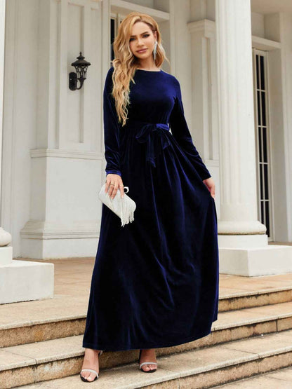 Woman in a navy velvet dress standing on steps outside a building