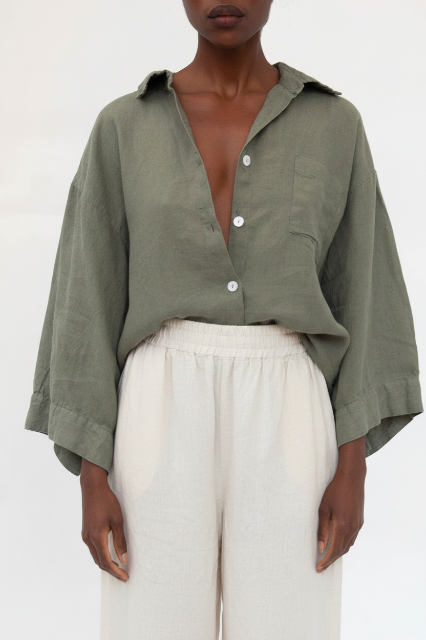 A model wearing an olive green linen button-down shirt with wide sleeves and white linen trousers, shot against a plain white background.