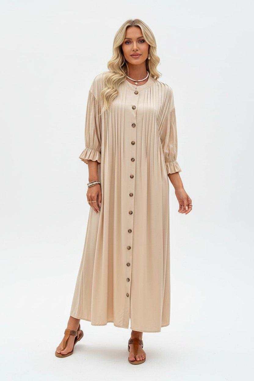 A woman modeling a beige midi-length pleated dress with three-quarter ruffled sleeves and a front button closure, paired with brown sandals, against a plain white studio background.