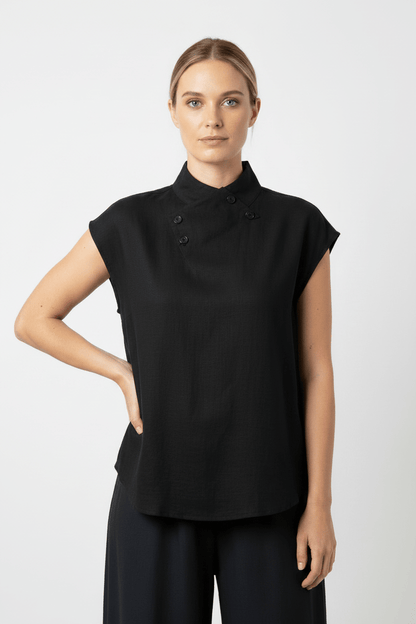 Woman wearing a black sleeveless top with buttons on a white background