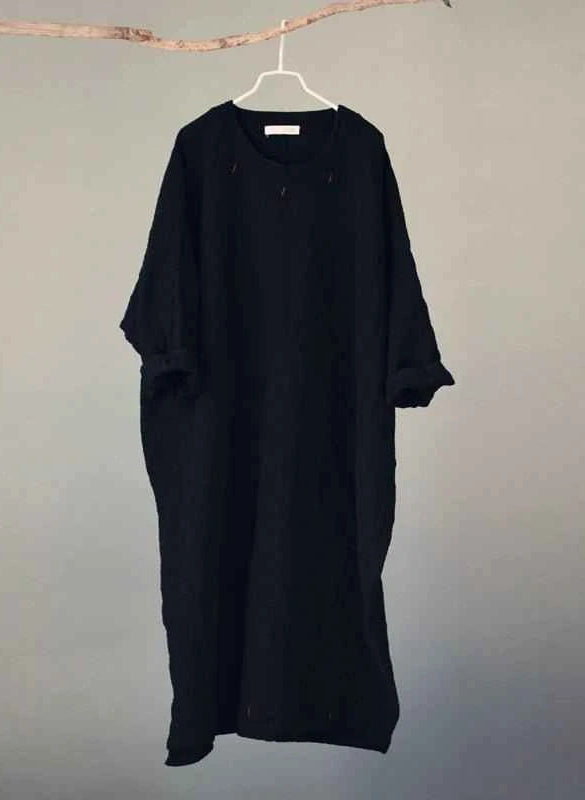 Black dress on a hanger against a plain background