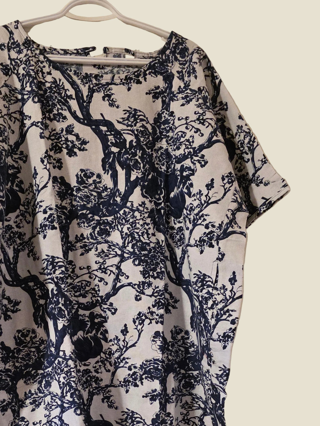 Navy floral patterned dress on a hanger against a white door.