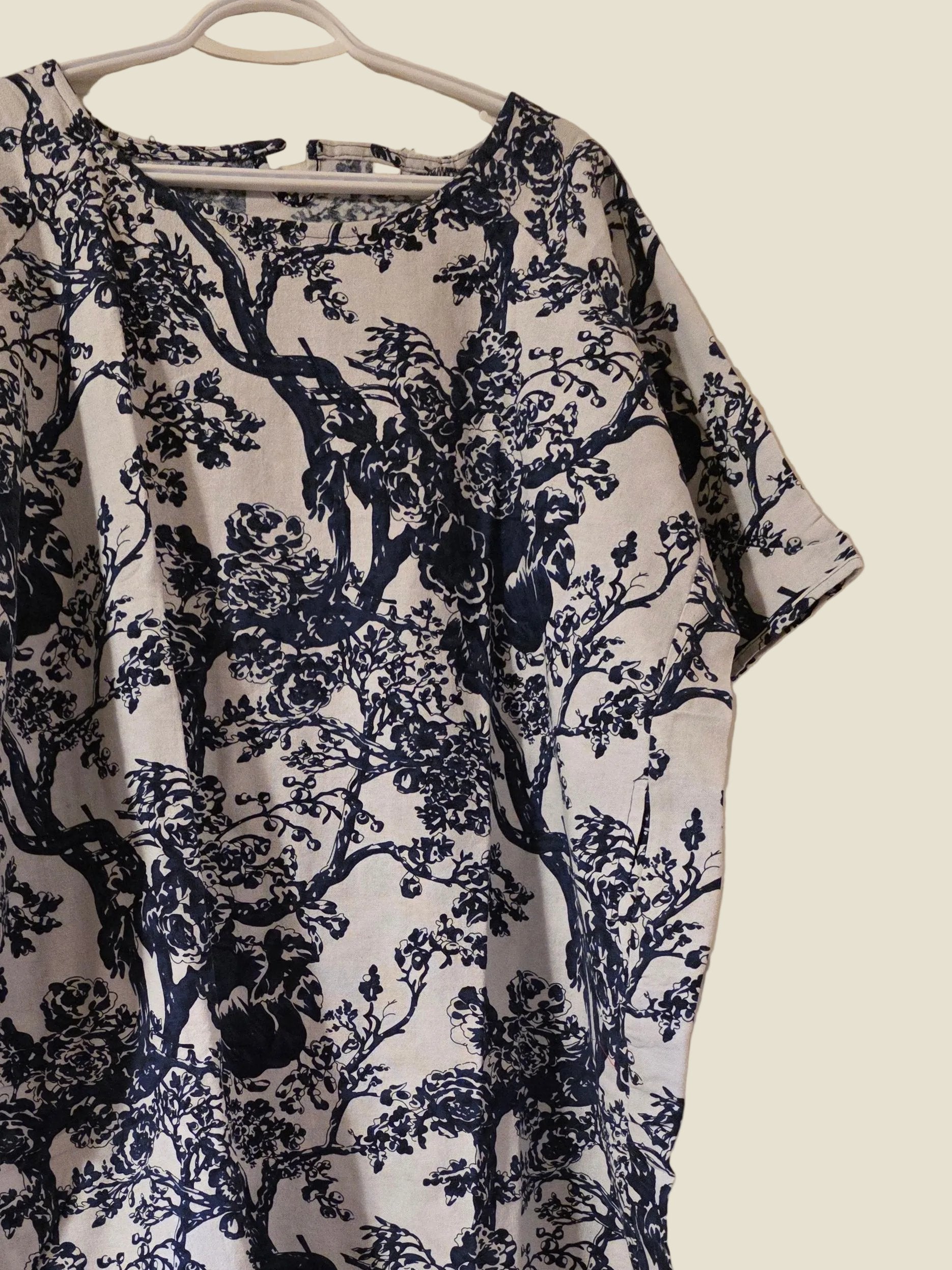 Navy floral patterned dress on a hanger against a white door.