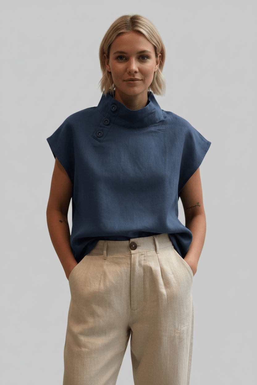 Woman wearing a blue sleeveless top and beige pants against a plain background