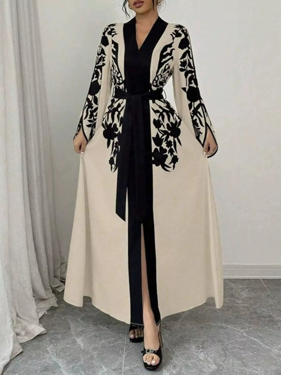 Woman wearing a black and white floral patterned cardigan over a black top and beige skirt.