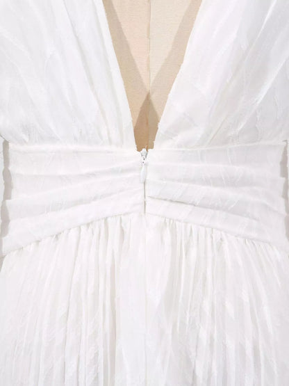Close-up of a white dress with a deep neckline and bow detail.