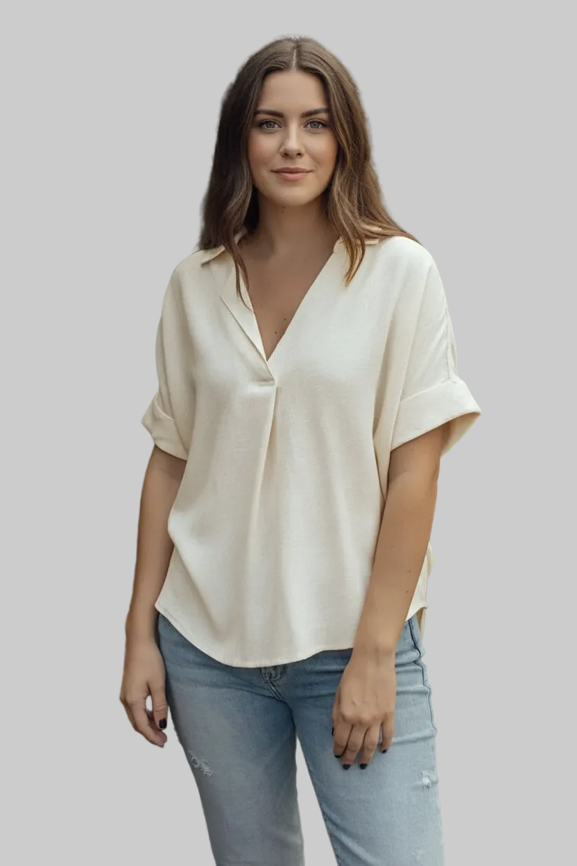 Person wearing a beige blouse and blue jeans against a natural background