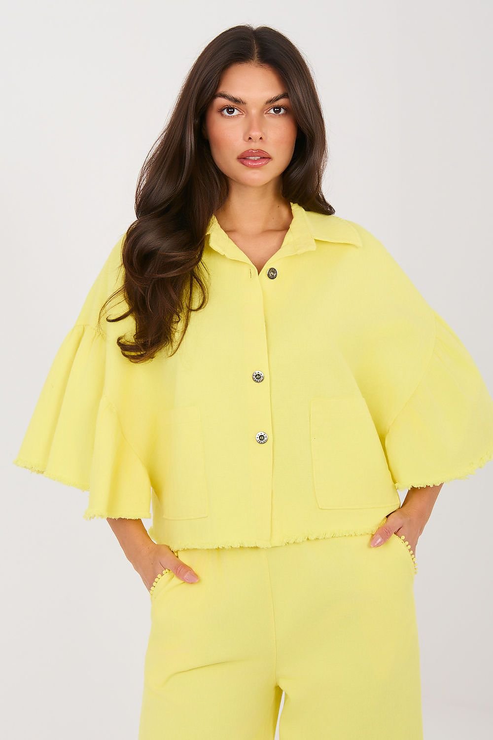 Woman wearing a yellow outfit with a cape-like top on a white background