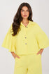 Woman wearing a yellow outfit with a cape-like top on a white background
