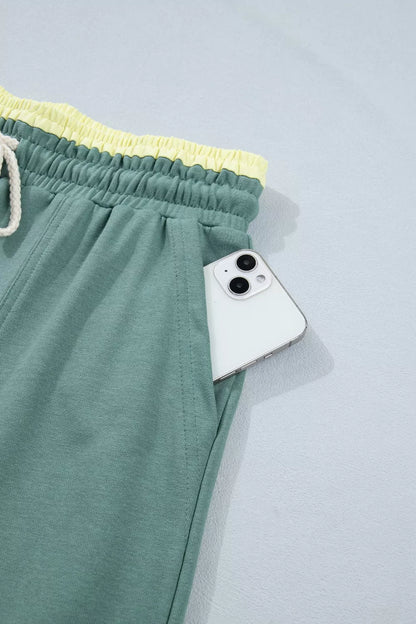 Green pants with a yellow waistband and a white phone on a light gray background
