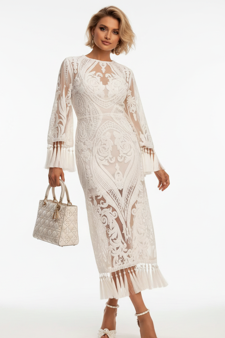 A woman models a long-sleeved cream lace midi dress with intricate floral embroidery and a fringed hem, holding a matching patterned handbag against a plain white studio background.