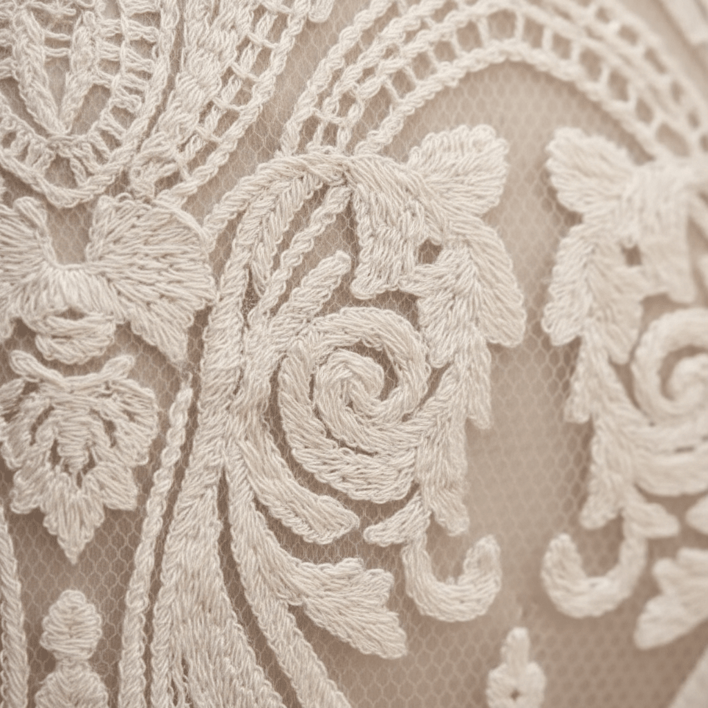 Close-up of an ivory lace fabric with intricate floral embroidery and mesh backing.
