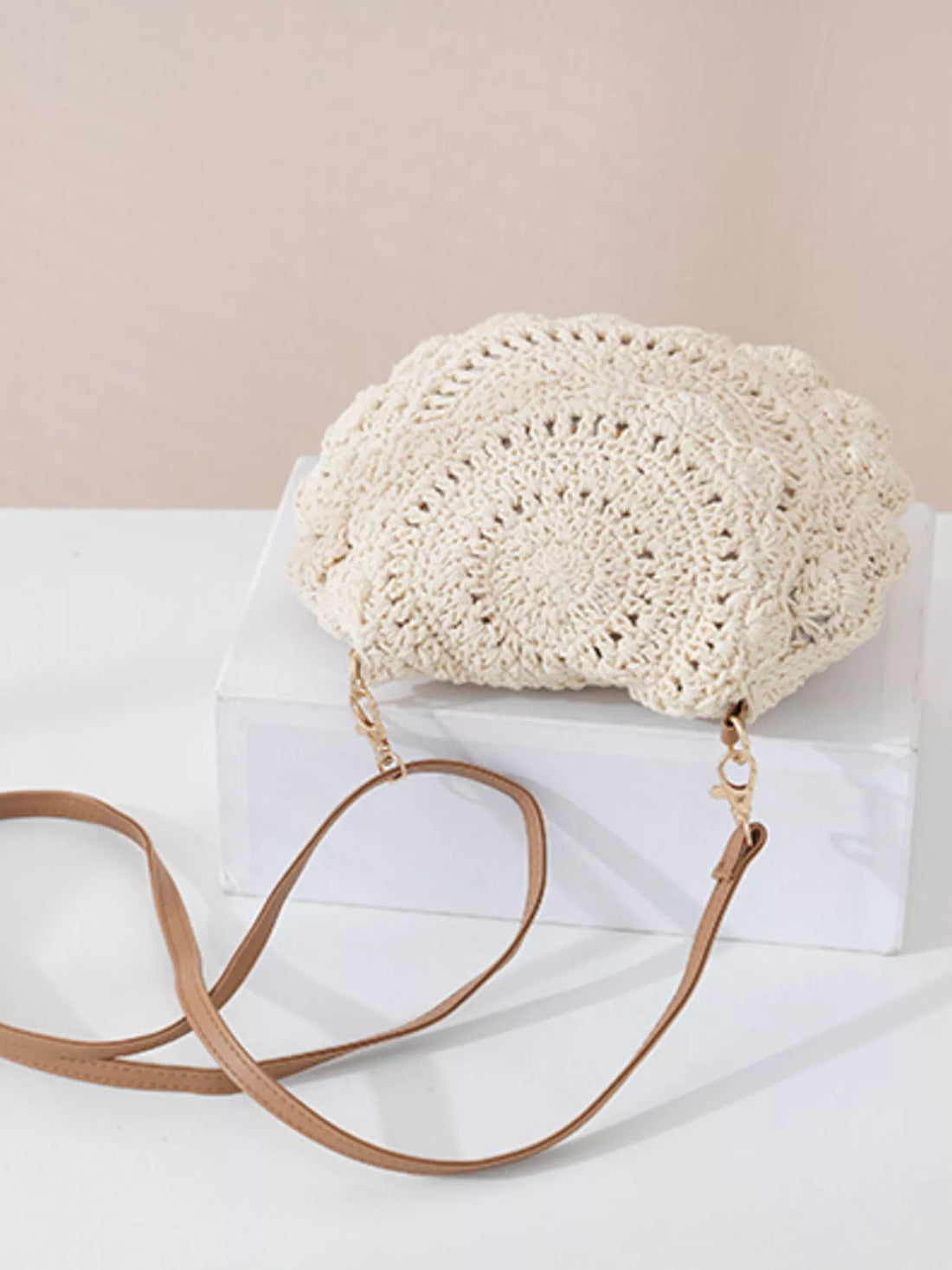 Crocheted handbag with a brown strap on a white surface