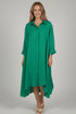 Woman wearing a green dress standing in a store with racks of colorful clothing.