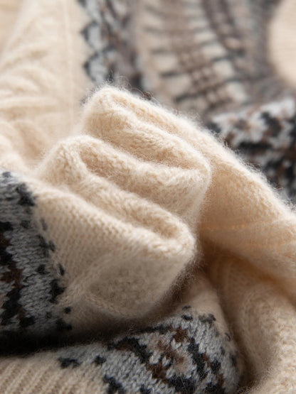 Close-up of a soft knit sweater or scarf in cream beige with a dark gray and brown Fair Isle patterned section.