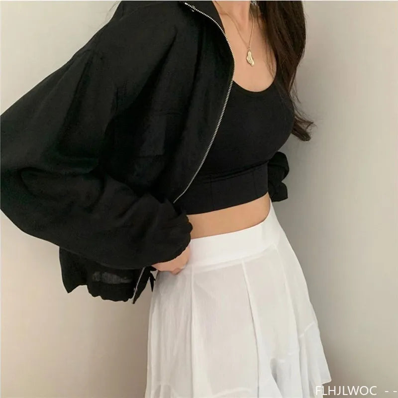 Person wearing a black jacket and white pants against a plain background