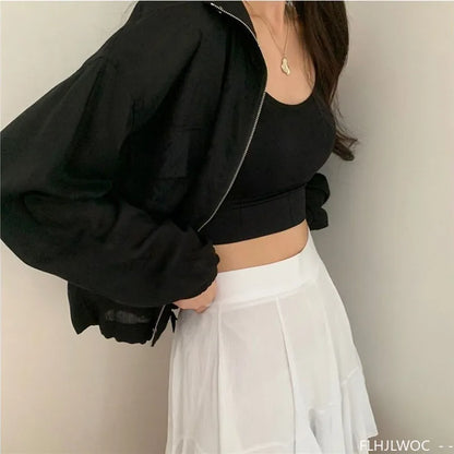 Person wearing a black jacket and white pants against a plain background